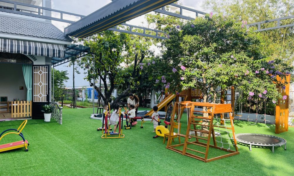 Bé lớp Sky tự tin tham gia trò chơi vận động thô trên sân cỏ rợp bóng cây tại trường Sunflower