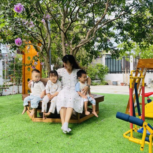 Cô giáo mầm non ôm ấp các bé lớp Sky trong vòng tay yêu thương dưới gốc cây bằng lăng rợp bóng mát